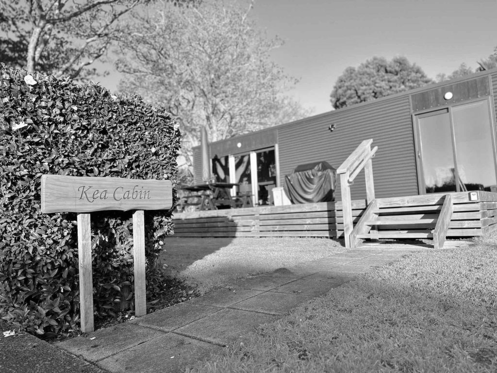 Black & White Exterior image of Kea Cabin Accommodation with sign at Heaven's Rest B&B