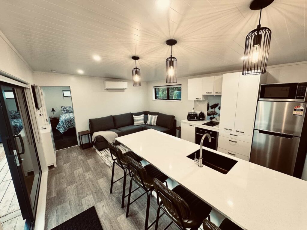 Fully equipped kitchen in Pūkeko Cabin with oven, fridge, and dining space – Heaven’s Rest B&B